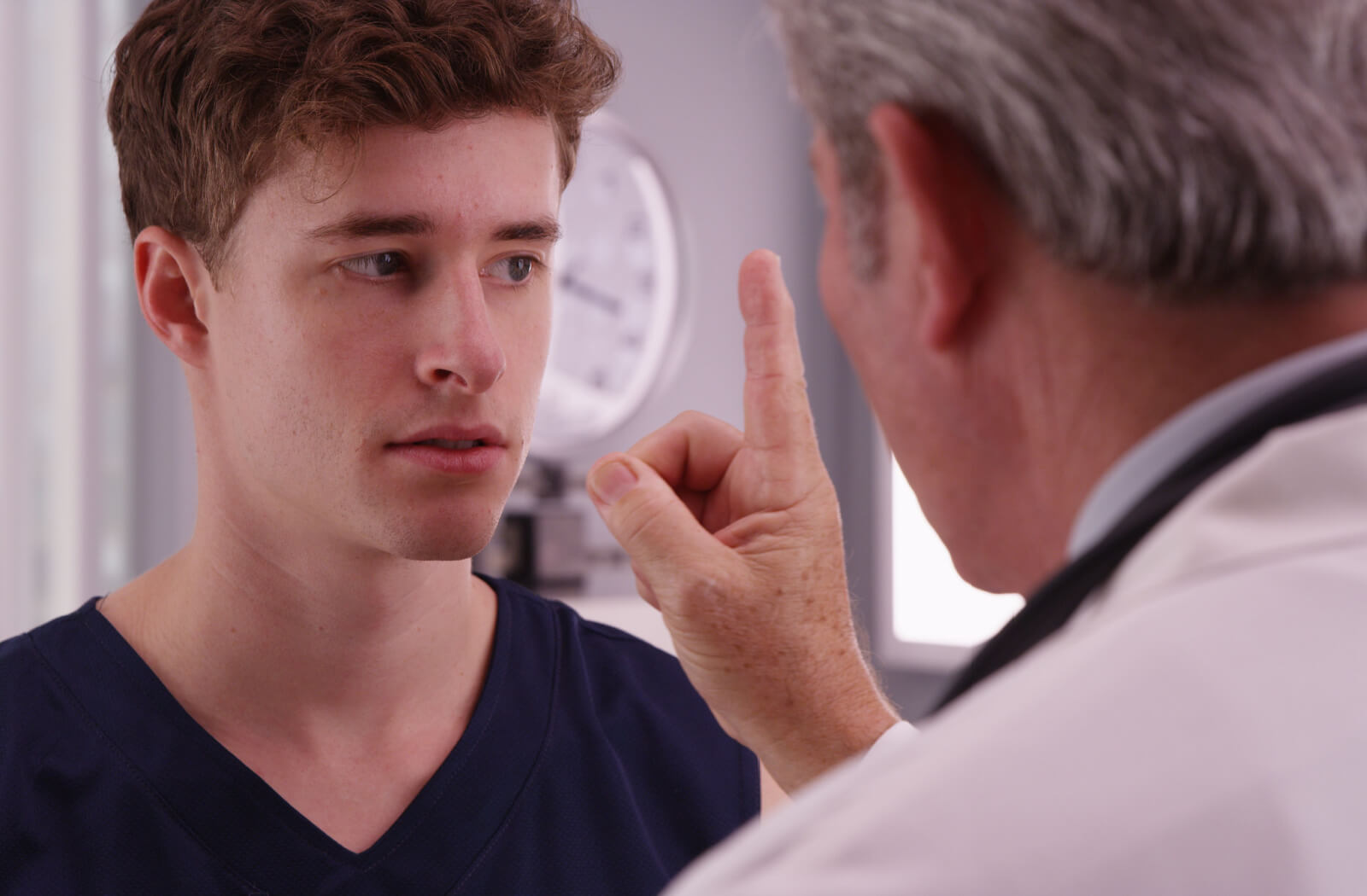 A young man looking at his doctor's finger during an eye-tracking exercise