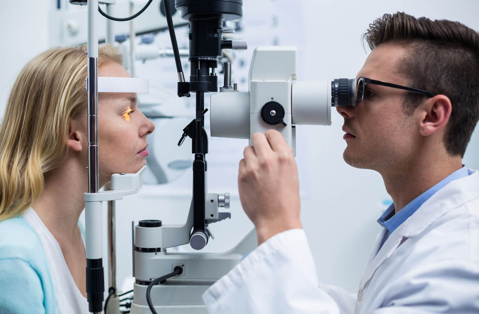 An optometrist performing a slit-lamp exam on his patient