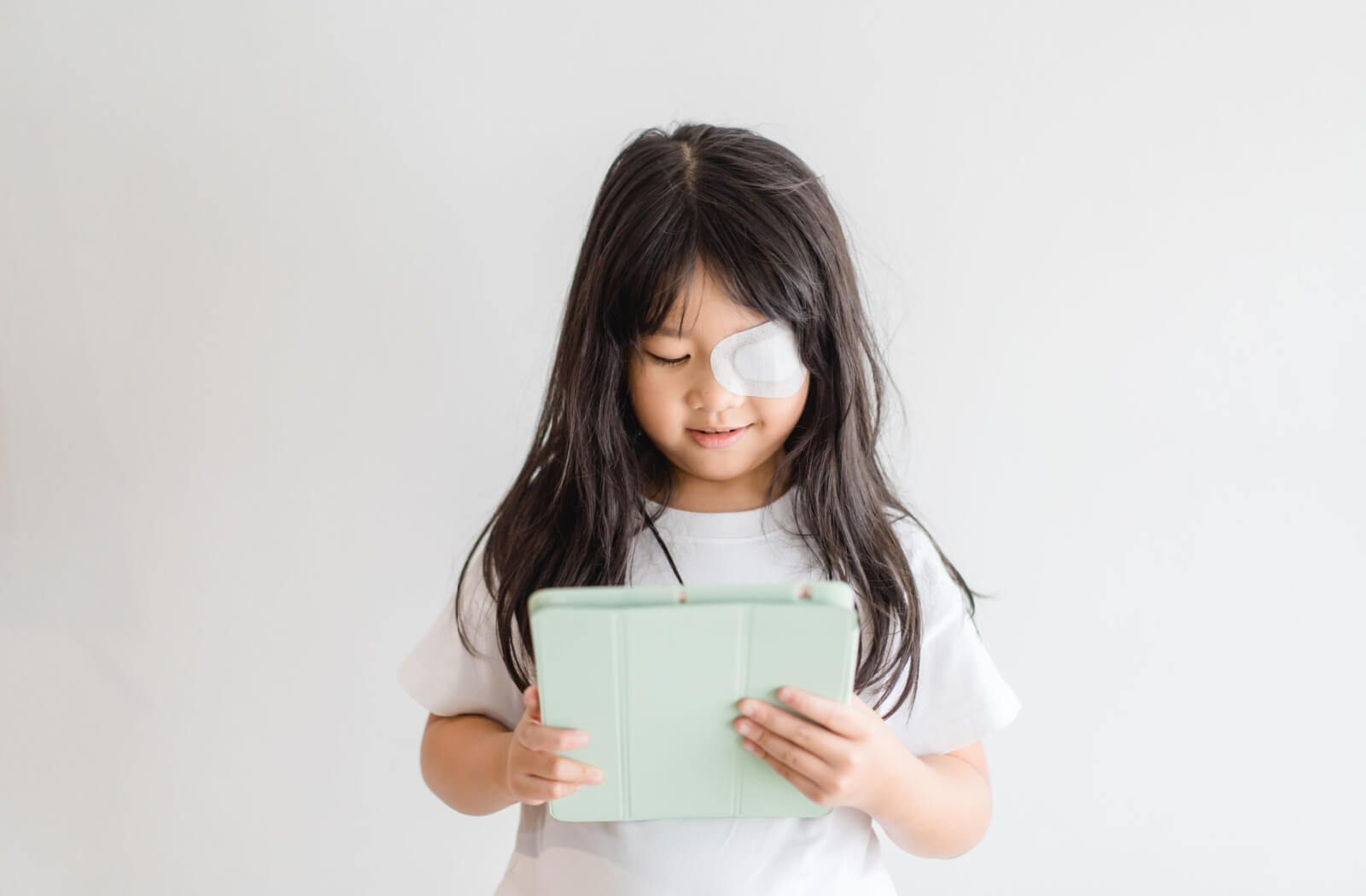 
A young girl with an eye patch while watching on her iPad.