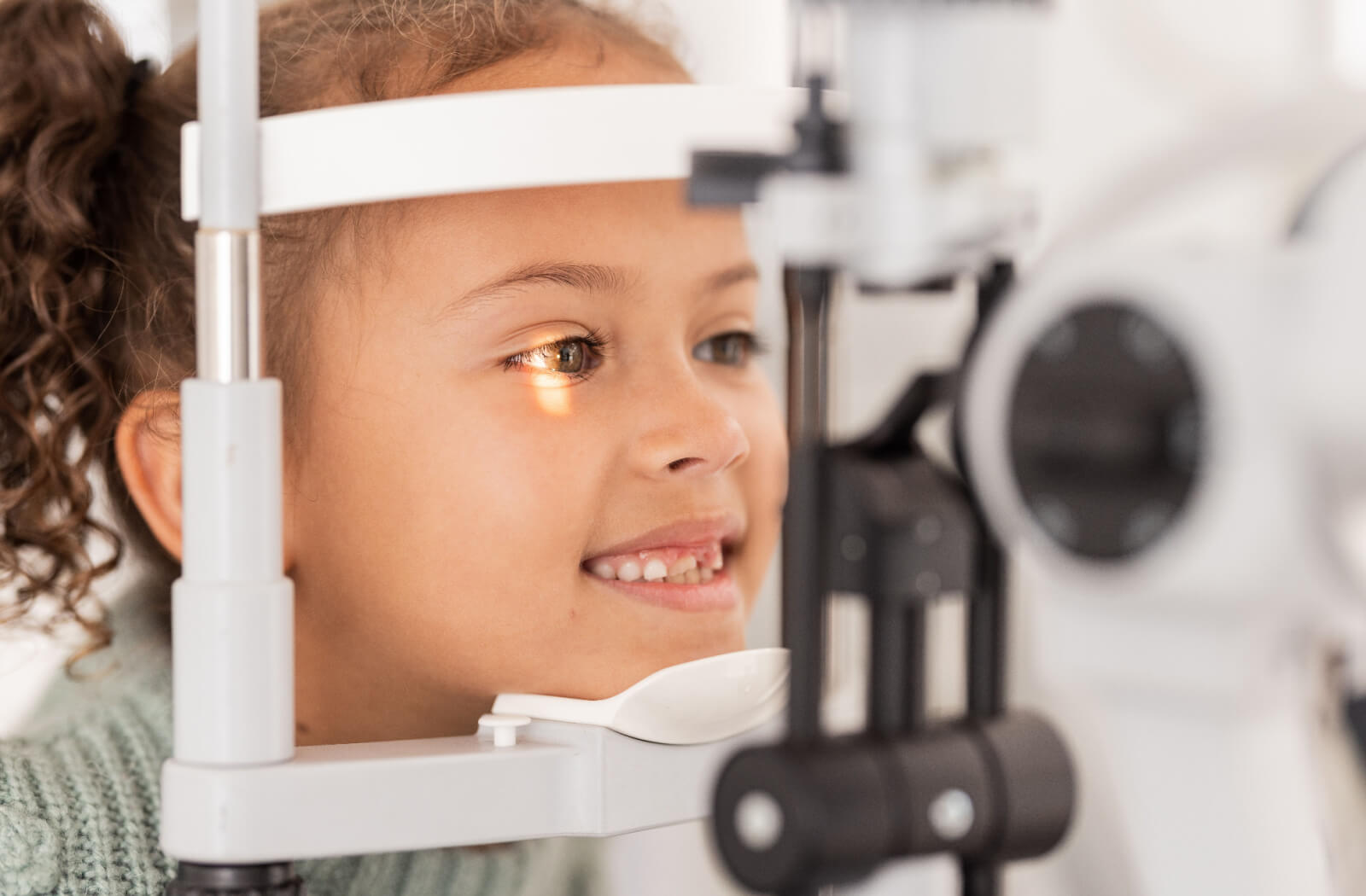 A girl is for an eye exam in the ophthalmologist's office with equipment for glasses. 