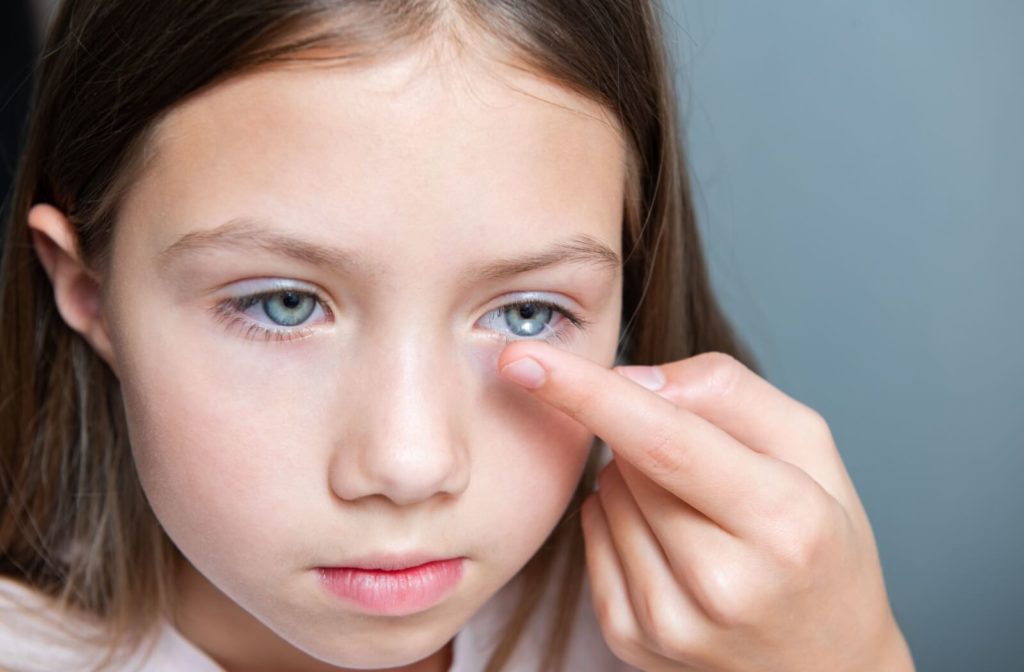 A young girl focusing as she places her MiYOSMART contact lenses onto her eye.