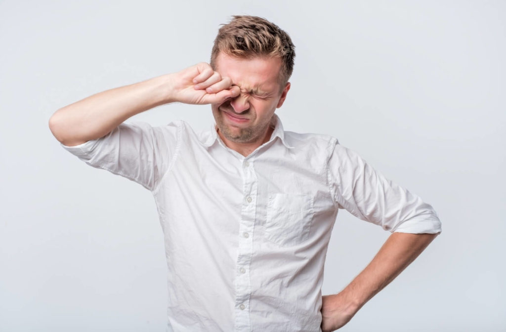 An adult patient vigorously rubbing their eyes because of severe dryness.